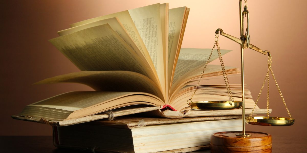 Gold scales of justice and books on brown background