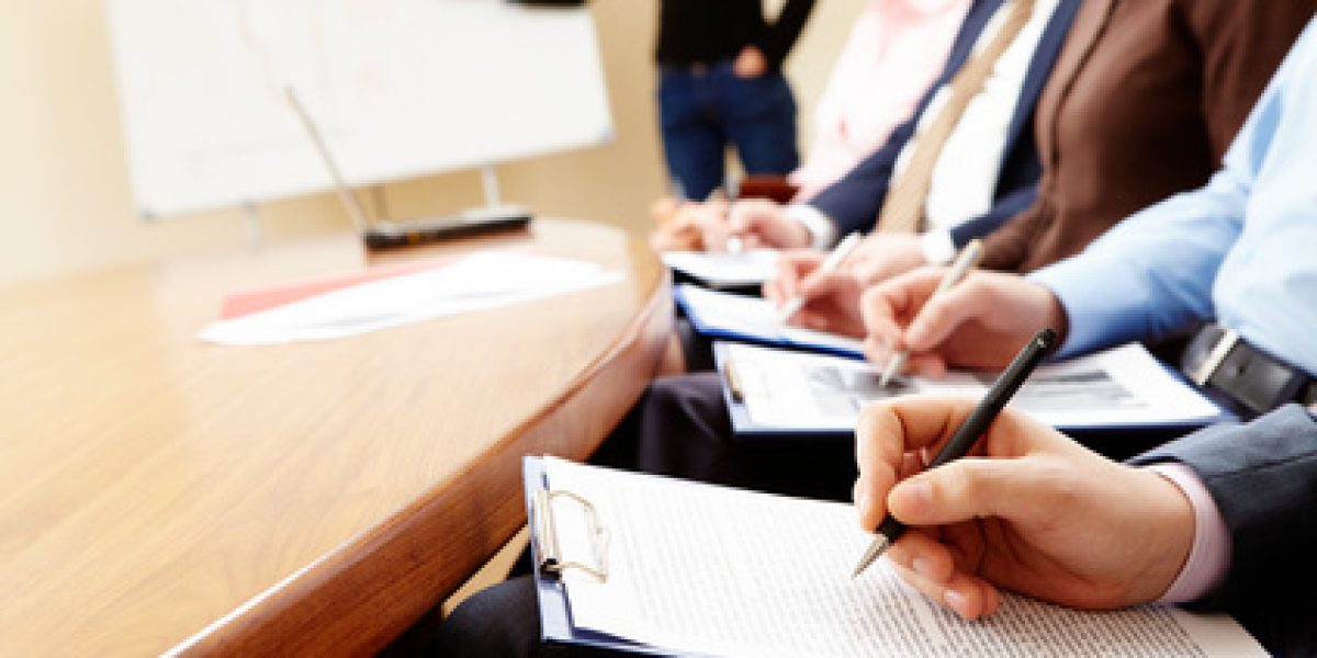 Close-up of businesspeople hands holding pens and papers near table at business seminar